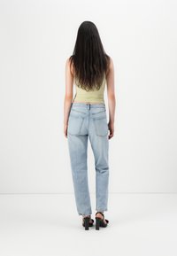 Light green tank top paired with high-waisted light blue denim jeans. Jeans feature a classic five-pocket design and a straight leg silhouette.