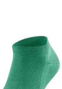 Grüne Knöchelsocke aus flexiblem Strickmaterial. Verfügt über einen gerippten Bund und eine glatte Textur, die darauf ausgelegt ist, bequem um den Knöchel zu sitzen.