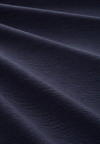 Granatowa tkanina o delikatnej, subtelnej strukturze, prezentująca miękkie fałdy i gładkie wykończenie. Idealna do zastosowań w odzieży lub tapicerce.