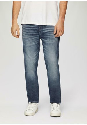 Heren denim jeans in donkerblauw met een lichte wassing. Rechte pasvorm met vervaging en contrasterende stiksels. Gemaakt in combinatie met witte sneakers.