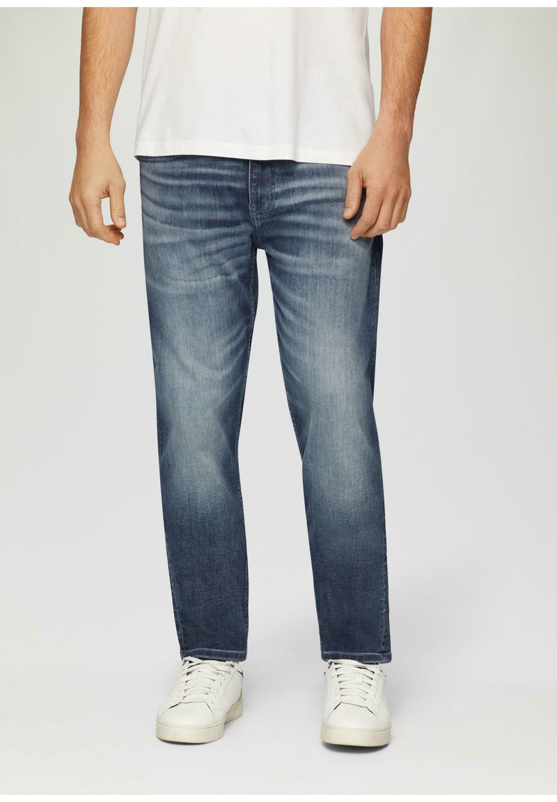 Heren denim jeans in donkerblauw met een lichte wassing. Rechte pasvorm met vervaging en contrasterende stiksels. Gemaakt in combinatie met witte sneakers.
