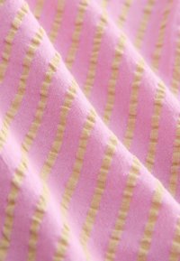 Vaaleankeltaruudullinen vaaleanpunainen kangas. Tekstuuri näyttää pehmeältä, jossa on kevyt poikittainen kuvio.