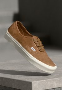 Bruine leren lage sneakers met witte rubberen zolen, ronde neus en vetersluiting. Bevat Vans-logo label aan de zijkant.