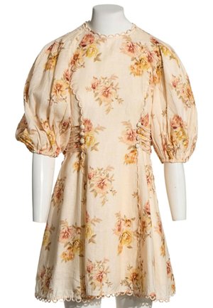 Robe fleurie crème avec manches courtes bouffantes, bords festonnés, détails de boutons sur les côtés et motifs de roses roses et jaunes sur le tissu.