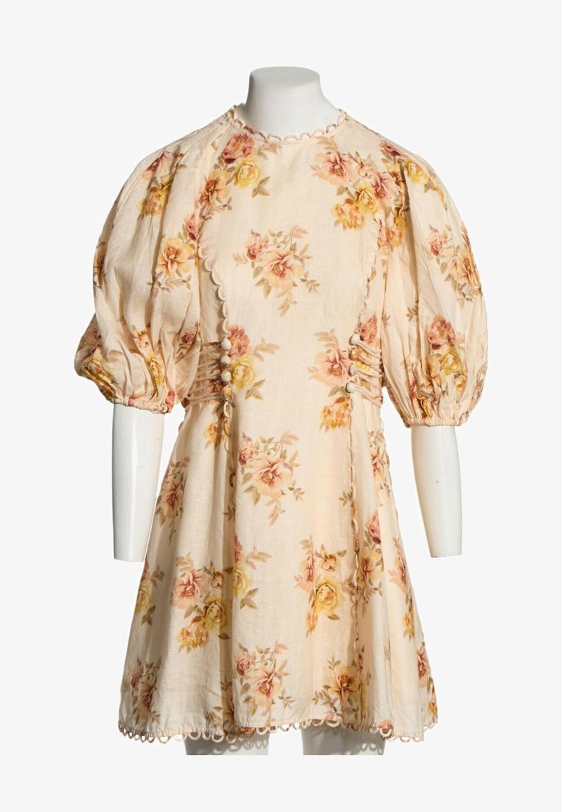 Robe fleurie crème avec manches courtes bouffantes, bords festonnés, détails de boutons sur les côtés et motifs de roses roses et jaunes sur le tissu.