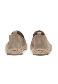 Chaussures slip-on en suede beige avec des détails en jute tissé le long de la semelle, présentant une texture douce et un design à dos bas.