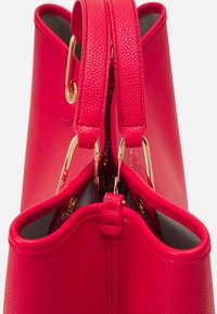 Czerwona torba na ramię z fakturowanej skóry, wyposażona w dwa solidne górne uchwyty oraz złote elementy ozdobne. Otwarty wierzch ułatwiający dostęp.