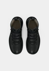 Scarpe alte nere con tomaia in pelle testurizzata, punta rinforzata, allacciatura e marchio discreto sulla soletta.