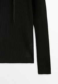 Haut noir à manches longues côtelé avec une silhouette ajustée, présenté sur fond blanc.