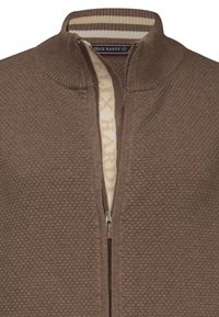 Cardigan marrone con zip, realizzato in tessuto testurizzato, colletto a coste e foderato in crema con motivo. Presenta una cerniera in argento per la chiusura.