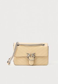 Κίτρινη τσάντα ώμου από δερματίνη με καπιτονέ ραφή, ασημένια αλυσίδα ως λουρί, με χαρακτηριστικό έμβλημα πουλιού ως κλείσιμο και λείο υλικό.