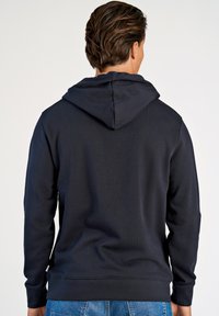 Donker marineblauwe hoodie met een kangoeroezak, geribbelde boorden en zoom. Gladde textuur en verstelbare trekkoord bij de capuchon.
