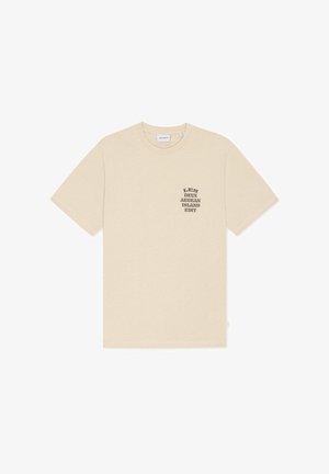T-shirt beige à manches courtes et col rond avec texte noir « LES DEUX AEGEAN ISLAND EDIT » sur la poitrine gauche.