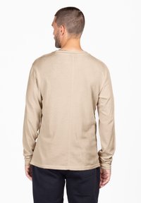 Camicia a maniche lunghe beige con scollatura rotonda e maniche aderenti, realizzata in un tessuto leggero e liscio. Design minimalista senza motivi.
