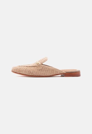 Beige vævet slip-on mule med lavt træhæl og guldkæde-detalje over vristen, på en ensfarvet hvid baggrund.