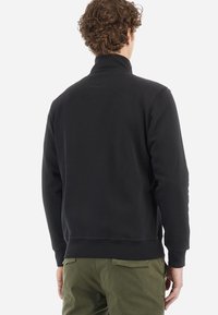 Černá mikina s vysokým límcem, hladkou texturou a žebrovanými manžetami. Na zadní straně je čistý design bez viditelných log nebo vzorů.