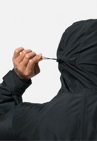 Zwarte lichtgewicht jas met een capuchon, die wordt aangepast door een hand die aan een trekkoord trekt. Kenmerkt zich door gladde stof en gestikte details.