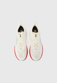 Λευκά αθλητικά παπούτσια με επάνω μέρος από δίχτυ, κόκκινη εξωτερική σόλα και ανοιχτό μπλε λεπτομέρειες. Διαθέτουν επενδυμένο γιακά και κορδόνια για ασφαλή εφαρμογή.