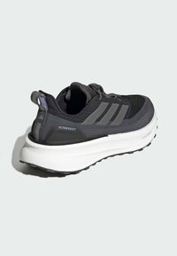 Chaussure de sport noire avec des accents gris, tige en mesh, semelle intermédiaire blanche rembourrée, semelle extérieure texturée, et branding à l'arrière et sur le côté.