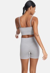 Siva rebrasti bralete s tankimi naramnicami in usklajenimi hlačkami visoke pasu. Gladka tekstura, prilegajoča zasnova in brezšivne robove.