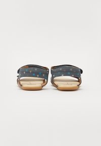 Blå sandaler med seilbåt mønster, justerbare remmer, åpen tå og beige fotbed. Lett gummisåle for holdbarhet og komfort.