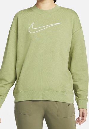 Personne portant un sweat Nike vert clair avec logo blanc et un pantalon vert assorti avec un petit logo Nike sur la poche.