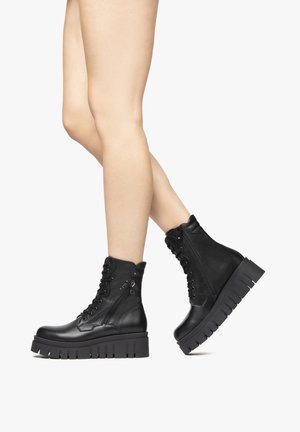 Black leather ankle boots with a chunky platform sole, lace-up front, and side zipper. Smooth texture and distinctive tread design.