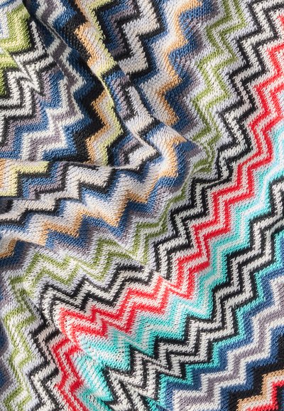 Gros plan sur un tissu tricoté multicolore avec des motifs en zigzag en noir, rouge, bleu, vert, orange et blanc.