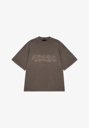 Tricou oversized din bumbac gri, cu guler rotund și mâneci scurte; prezintă o grafică mare, subtilă "PEGA DOG" pe partea din față.