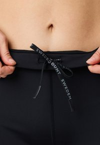 Pantaloni da bagno neri con chiusura con coulisse caratterizzati dal marchio "SWEDEM". Texture liscia, design aderente e una vita rifinita in modo pulito.