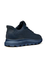 Sneakers atletici blu navy con una parte superiore in maglia testurizzata e dettagli in pelle liscia. Suola spessa e ondulata per ammortizzazione e supporto.