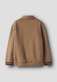 Ruda, be apykaklės striukė su lygiu paviršiumi, ribotomis rankogaliais su juodomis juostelėmis ir laisvo kirpimo. Rodoma nugaros pusė.