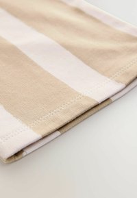 Gestreepte katoenstof met afwisselend beige en lichtroze kleuren. De rand heeft een nette gestikte zoom met een zachte textuur.