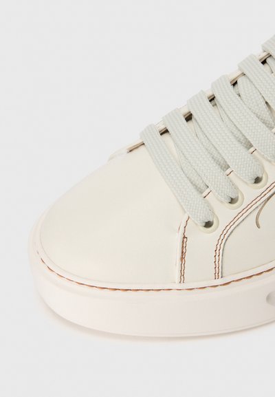 Sneaker bianco in pelle con punta arrotondata, lacci testurizzati grigio chiaro e dettagli di cucitura a contrasto lungo la suola.