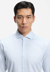 Camicia a quadri azzurri con bottoni e colletto, caratterizzata da un motivo a griglia e bottoni bianchi, realizzata in tessuto morbido.