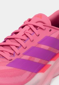 Close-up of bright pink athletic shoe with purple stripes, pink laces, and cushioned sole.