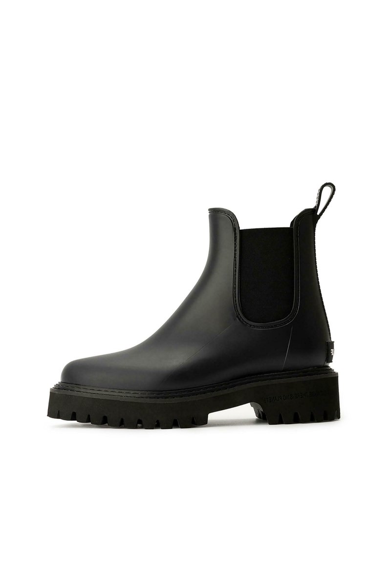 Schwarzer Gummichelsea-Boot mit elastischen Seitenpaneelen, strukturiertem schwarzen Gummisohle und einer Schlaufe an der Rückseite für einfaches Anziehen.