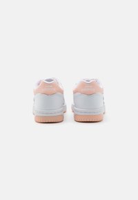 Baskets blanches avec des accents roses, dotées d'un col rembourré, d'une semelle en caoutchouc texturé et de la marque "New Balance" sur le talon.