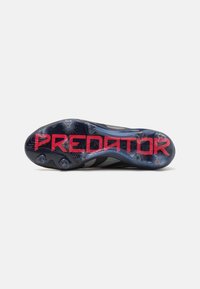 Predator fodboldsko sål, sort med en blå gradient, har rød tekst, støbt knopper og en tekstureret overflade for greb.