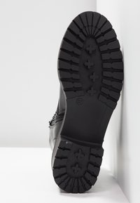 Suola di stivale nera con motivo di battistrada spesso e robusto. Presenta una texture liscia, materiale resistente e un design minimalista e funzionale.