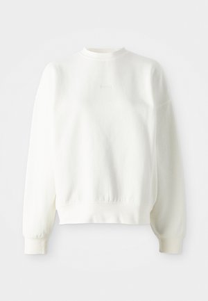 Bijela dukserica dugih rukava, s okruglim izrezom i rebrastim manžetama. Ima urezani logo u sredini i teksturiranu tkaninu.