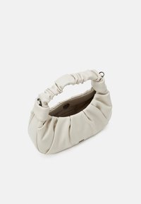 Sac à main beige clair en matériau doux, avec une texture froncée, une poignée courbée et une fermeture à bouton unique à l'intérieur.
