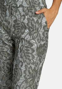 Kanten broek met een ingewikkeld bloemenpatroon in grijstinten. Heeft een gestructureerd oppervlak en zijzakken, ontworpen voor comfort.
