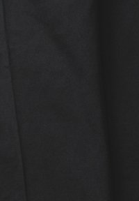 Tissu noir avec une texture lisse et un motif discret de tissage diagonal, présentant de douces plis et ombres.