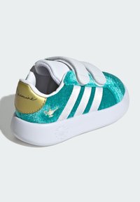 Tyrkysové tenisky s flitrami a bielymi suchými zipsami, bielou podrážkou a zlatým akcentom na päte s menom "Jasmine." Na boku sú tri biele pruhy.