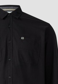 Zwarte button-up shirt met kraag, twee borstzakken en een klein logodetail. Gemaakt van een gladde stof met een klassieke pasvorm.
