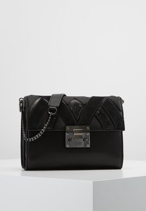 Sac à bandoulière noir en cuir et tissu avec bandoulière chaîne argentée, rabat à motif géométrique et fermoir argenté gravé du logo Guess.