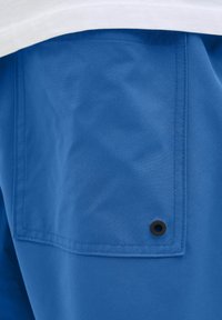 Blauwe shorts van glad materiaal, met een achterzak met zwart hardware detail en zichtbare stiksels.