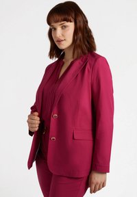 Blazer fucsia realizzato in tessuto morbido, con design a un bottone, due tasche frontali e bottoni dorati per la chiusura.