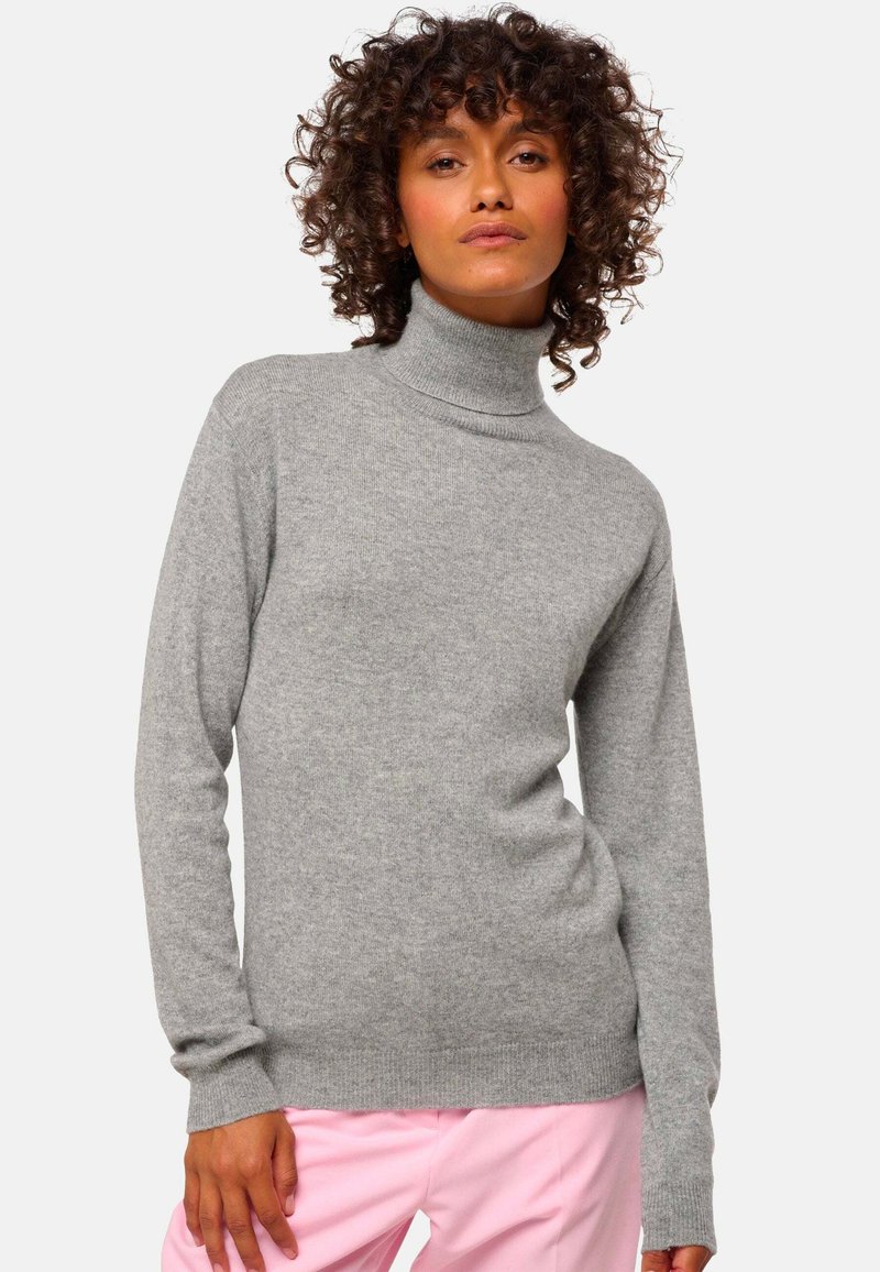 Un pull à col roulé gris en tissu doux avec des manches longues, des poignets côtelés et une coupe ajustée, assorti à un pantalon rose.
